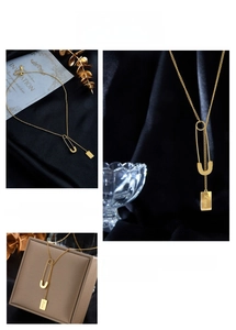 Detailed view of a gold chain necklace with a pin pendant and engraved love square tag