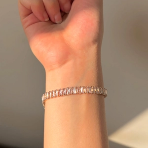 Close-up of rose gold bracelet with clear rectangular zircon crystals on woman's wrist