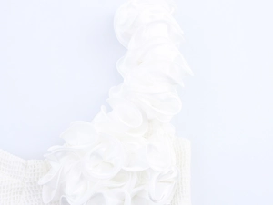 Détail des volants en satin blanc superposés et du tissu en maille sur le haut