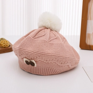 Detail of pink knitted beret featuring a soft white faux fur pom-pom and bow embroidery