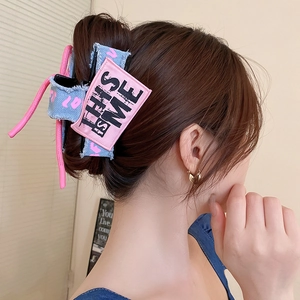 Detail of pink and blue denim bow hair claw clip with embroidered label on hair