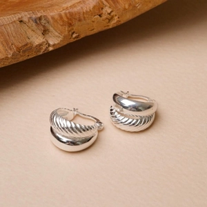 Macro shot of 925 sterling silver hoop earrings with unique twisted rope and polished texture
