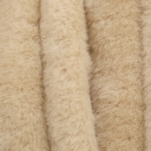 Gros plan sur la texture de fausse fourrure beige douce avec densité et éclat soyeux