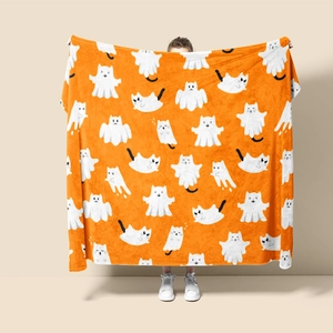 Detail of soft orange flannel blanket with festive white ghost cat patterns