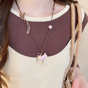 Close-up of a cute cartoon cat pendant with striped sweater and floral detail on long cord