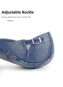 Close-up of adjustable silver metal buckle and embroidery on washed blue denim hat