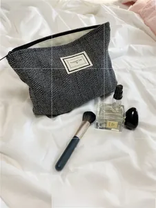 Close-up of herringbone tweed makeup bag with Pleasant Time tag and black zipper