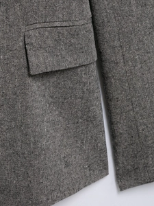 Macro close-up of grey tweed blazer fabric showing flap pocket detail and woven texture