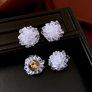 Detail shot of crystal flower cluster earrings with silver needle on black leather surface