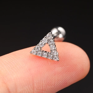 Macro shot of a hollow triangle zircon stud earring on fingertip with black background