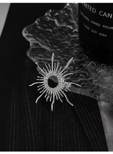 Detail of silver sunburst brooch with pavé zircons on textured glass and fabric