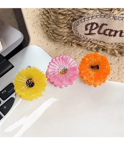 Close-up of yellow, pink and orange daisy flower hair clips in a glossy resin finish