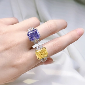 Macro detail of emerald cut purple and yellow high carbon diamond rings on model hand