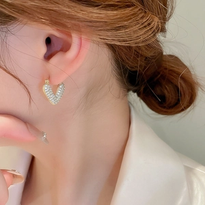 Detail view of gold heart drop earrings with pave zircons worn by a female model