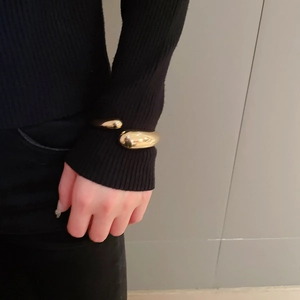 Detailed view of a gold-plated teardrop open cuff bracelet with a polished finish