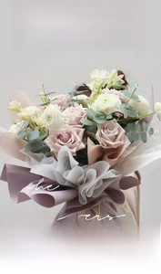 Detail of elegant bouquet wrapped in grey-purple milk cotton paper with ribbons