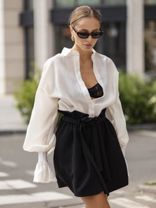 Elegant white long sleeve shirt paired with high waist black belted shorts for urban style