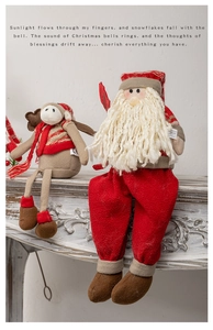 Detail of Christmas plush figurines showing Santa and reindeer on white wooden fireplace