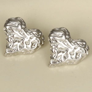 Macro shot of silver heart studs featuring unique hammered texture and metallic finish