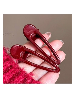Detail of dark red geometric hollow hair clips with glossy finish on hand