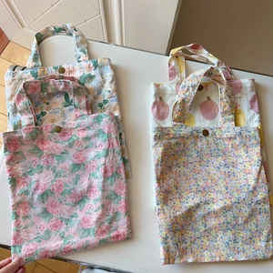 Detailed top view of four floral cotton handbags with metal snap buttons on a white desk