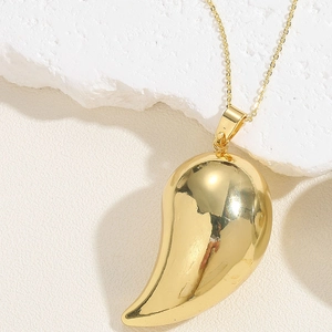 Macro shot of a 14K gold-plated teardrop pendant on a white stone background