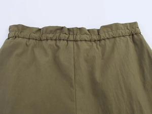 Detail of olive green woven shorts featuring elastic waistband and precise stitching