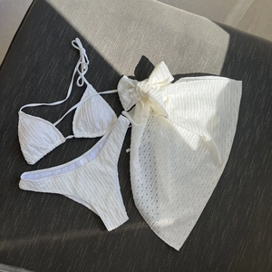 Three-piece white bikini set with halter top and matching sarong in textured knit fabric