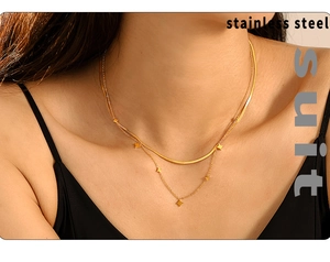 Detail einer zweilagigen goldenen Edelstahl-Schlangenkette mit Sternanhänger am Hals