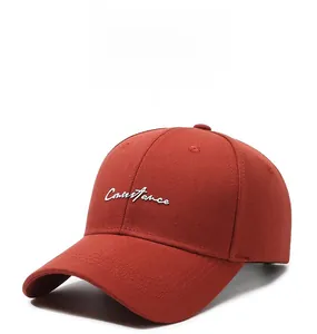 Detail of white Constance embroidery on a brick red cotton twill baseball cap