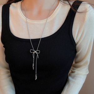 Detail of silver bow pendant necklace styled on a model against a black background