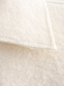 Macro view of plush off-white wool fabric showing texture and stitching details