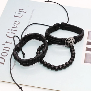 Detail of 3-piece vintage men's black leather and wooden bead bracelet set with tree of life charm