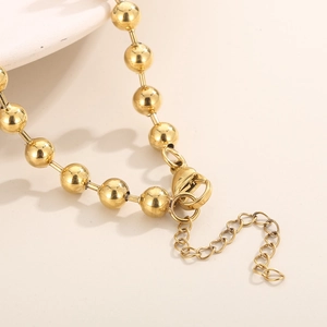 Detail of golden bead chain necklace featuring a secure lobster clasp and extension link