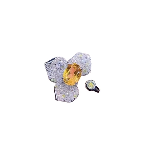 Luxurious flower ring with yellow gem center and micro-paved diamonds in silver setting