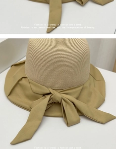 Detail view of khaki straw sun hat featuring a large fabric bow and fine woven texture