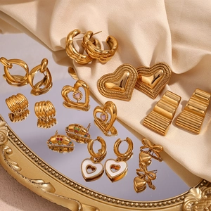 Detailed collection of vintage 18K gold plated heart earrings on beige satin fabric