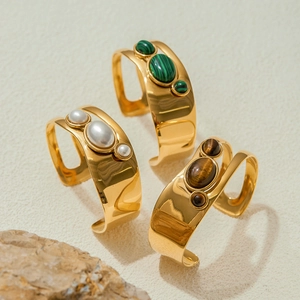 Dettaglio di bracciali dorati con malachite, perle e pietre occhio di tigre