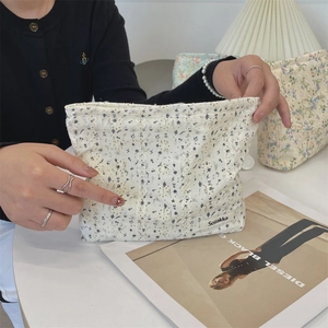 Detail einer floralen Baumwoll-Kosmetiktasche mit Spitze, die in der Hand gehalten wird