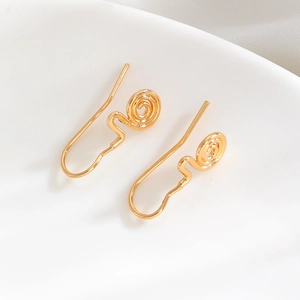 Macro shot of minimalist golden swirl earrings with a polished finish on white porcelain