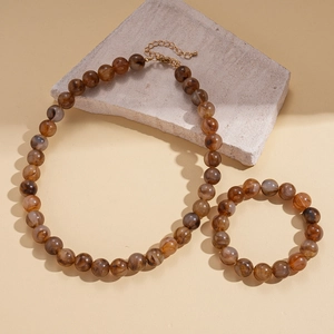 Detailed shot of amber resin beads necklace and bracelet set on a textured stone base