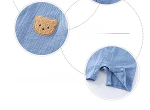 Detail of light blue gauze baby bodysuit with teddy bear patch and metal snap buttons