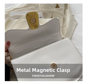 Detailed close-up of the durable gold magnetic closure and fine stitching on a white crossbody bag
