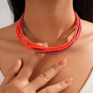Close-up of bohemian layered necklace with vibrant red and purple glass seed beads
