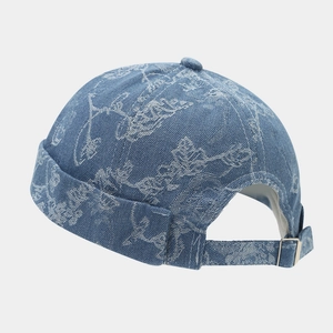 Detail of blue denim brimless cap showing white floral patterns and metal buckle