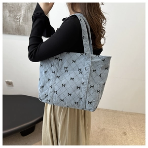 Détail d'un sac cabas en velours côtelé bleu clair avec motifs de nœuds noirs porté