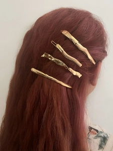 Close-up of four gold irregular wavy metal hair clips on red hair in a set of four