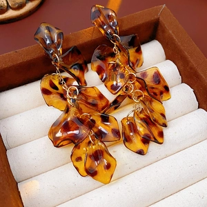 Close-up of leopard print resin tassel earrings on a soft beige cushion inside a jewelry box