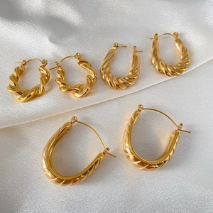 Three pairs of gold-plated stainless steel twisted hoop earrings on white silk