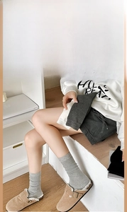 Detail of ribbed knit mid-calf socks in grey cotton worn with suede fur-lined clogs